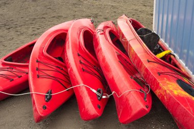 Boş kırmızı plastik eğlence kayaks Kiralık veya Kiralık, yağmurlu bir günde tarihinde saat sonra kumsalda depolanan. Hilal Beach, Surrey, British Columbia, Kanada.