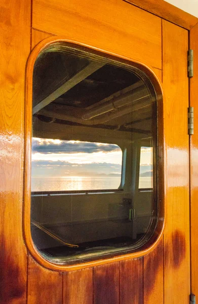 Круїзний корабель важкі дерев'яні лаковані зовнішні двері з вікном, що відображає море . — стокове фото