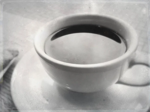 Black coffee in white ceramic cup and saucer in a cafe under natural light. — Stock Photo, Image