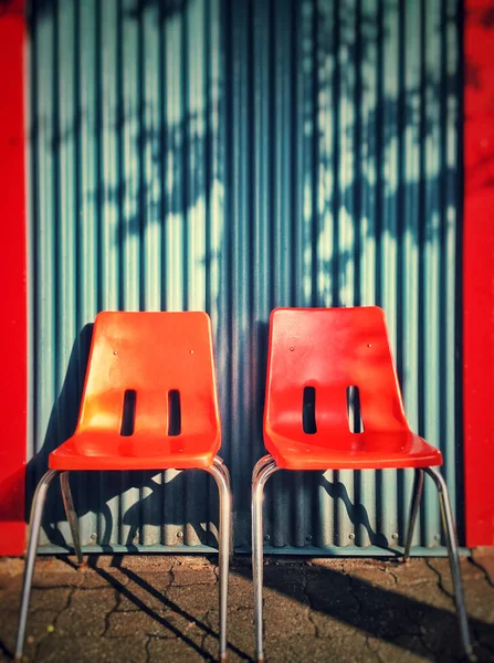 Bir mavi dalgalandırmak duvara iki modern turuncu plastik sandalye. — Stok fotoğraf