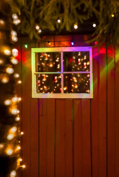 Luzes de Natal refletidas na janela velha de vermelho rústico pintado w — Fotografia de Stock