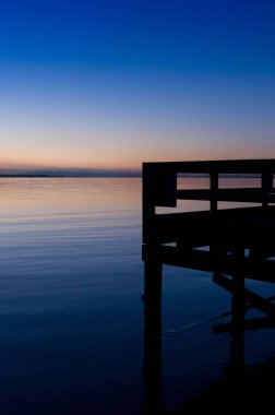 Sakin okyanus dusk mavi saat içinde bay bakan pier silüeti.