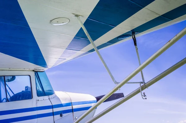 Sotto l'ala di piccoli aerei vintage a strisce blu e bianche con cielo blu soleggiato . — Foto Stock