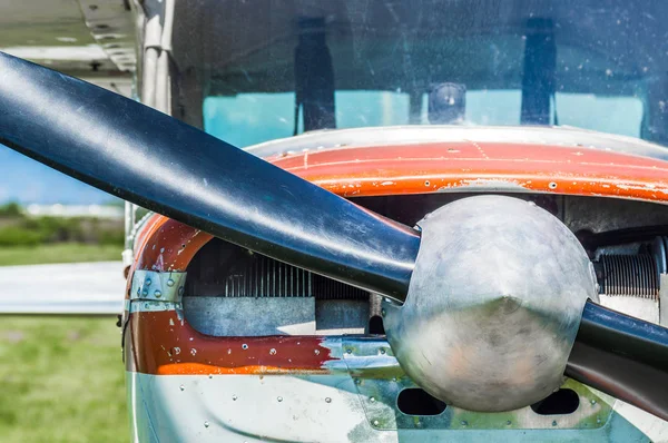 Pequena aeronave utilitária leve, tinta vermelha e branca desgastada, vista frontal com hélice no dia ensolarado . — Fotografia de Stock