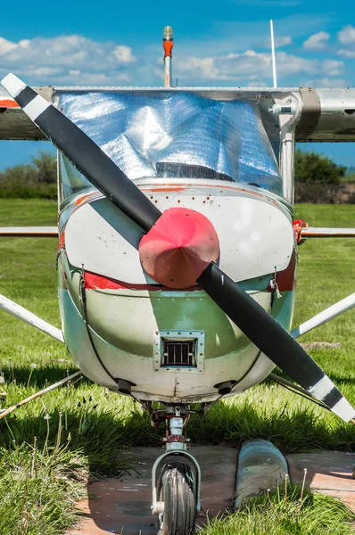 Velho avião de hélice de motor único vermelho e branco, vista frontal, estacionado no campo de grama . — Fotografia de Stock