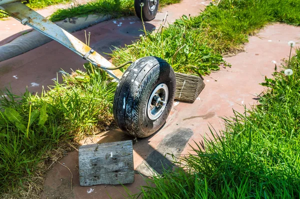 Old small single engine airplane wheel and wooden chocks on parking pad.