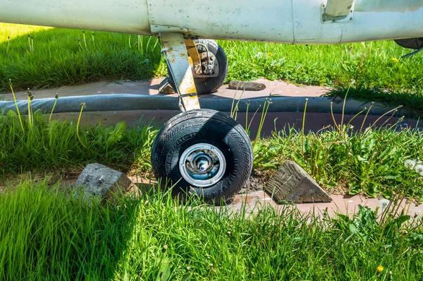 Vecchio piccolo monomotore ruota aeroplano e blocchi di legno sul tappetino di parcheggio . — Foto Stock