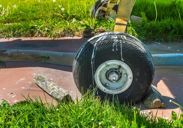 Old small single engine airplane wheel and wooden chocks on parking pad.