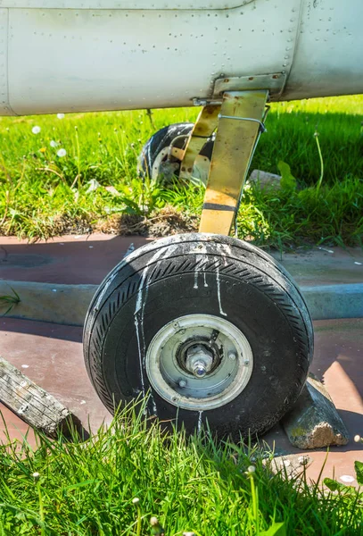 Vecchio piccolo monomotore ruota aeroplano e blocchi di legno sul tappetino di parcheggio . — Foto Stock