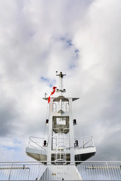 Ship navigation tower mast with Canadian flag and cloudy sky.