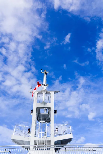 Barco blanco torre de comunicación mástil, vista trasera desde abajo con bandera canadiense contra el cielo azul nublado . —  Fotos de Stock