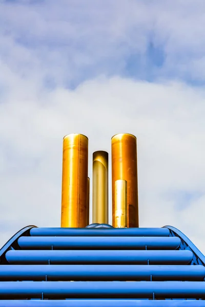 Vista frontal gráfica simples dos tubos de escape do navio e capuz azul contra o céu azul com nuvens . — Fotografia de Stock