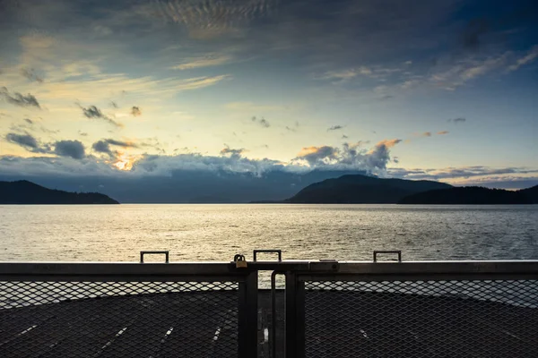 Ανατολή ηλίου πάνω από τον ωκεανό και τα βουνά από μπροστά από το κατάστρωμα του πλοίου, Χόου ήχος κοντά Γκίμπσον, Καναδάς. — Φωτογραφία Αρχείου