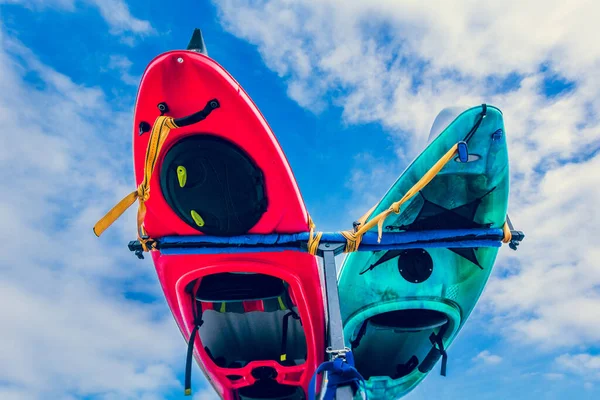 Parte inferior de los kayaks atados al bastidor en la parte posterior del vehículo contra el cielo azul con nubes —  Fotos de Stock