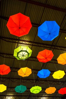 Endüstriyel yapının metal tavanından sarkan parlak renkli şemsiyeler