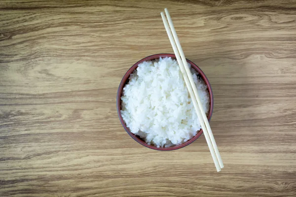 Ahşap zemin üzerinde siyah bir kasede pirinç sıcak yemek çubukları