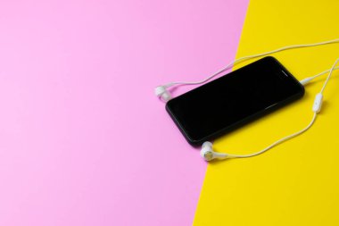Akıllı telefonlar ve kulaklıklar sarı ve pembe arka planda vintage müzik dinleyin.