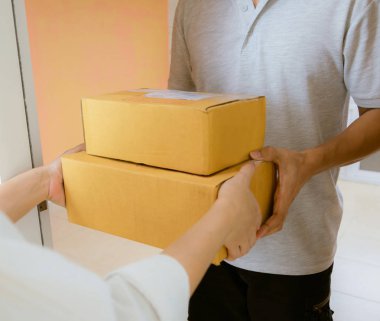 Teslimat personeli üniforması teslimattan bir paket teslim alıyor.
