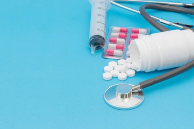 Mavi arka planda tıbbi steteskop ve enjeksiyon.