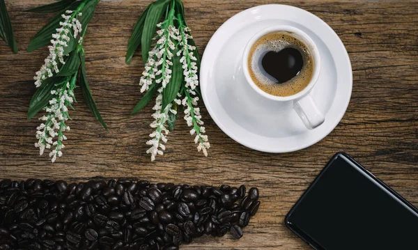 Heart coffee and coffee beans roasted in a sack on a wooden floor.