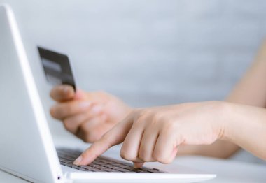 Bilgisayardan alışveriş yapan elleri klavyede tutuyor.
