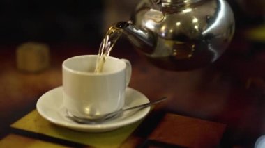 Bir çaydanlık üzerinden bir bardak sıcak çay akar