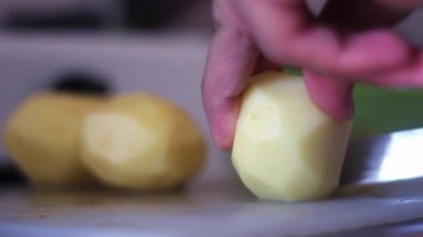 Tahtada bıçak olan bir adam patates kesiyor.