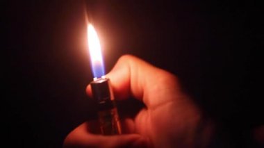 Siyah arka planda çakmağı olan bir el.