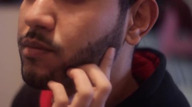 Siyah sakalını kaşıyan bir adam.