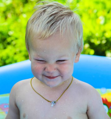 Çocuk doğada bir şişme havuzunda yüzüyor.