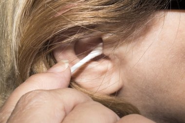 Bir kadın bir pamuklu çubukla kulaklarıyla temizler. Adam arka plan kulakları temizler.