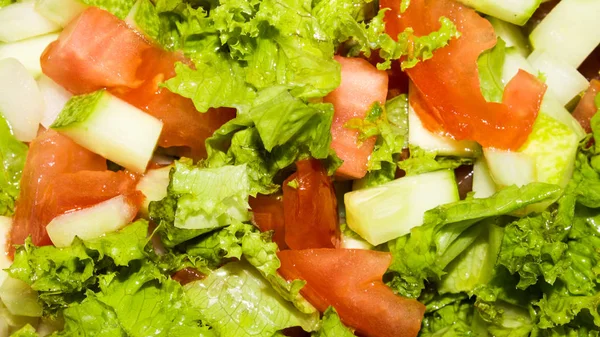 Tomato, cucumber and lettuce salad.Light salad with fresh vegetables.Background of vegetable salad.