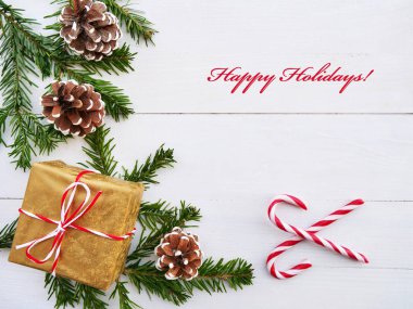 Beyaz ahşap zemin üzerinde şeker kamışı, Hediyelik, koni ve çam dalları ile Noel tebrik kartı.