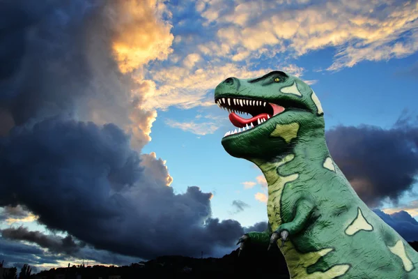 Tyrannosaurus-rex modelo contra un cielo atardecer con nubes de tormenta —  Fotos de Stock