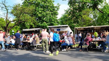  İnsanlar açık havada masalarda yiyor ve içiyorlar