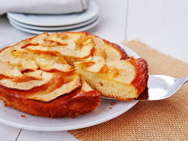 Apple cake on white plate with one slice on a cake server. — Stock Photo, Image