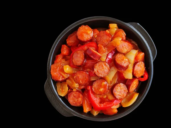 Guisado de legumes com fatias de salsicha picantes em tigela preta isolada — Fotografia de Stock