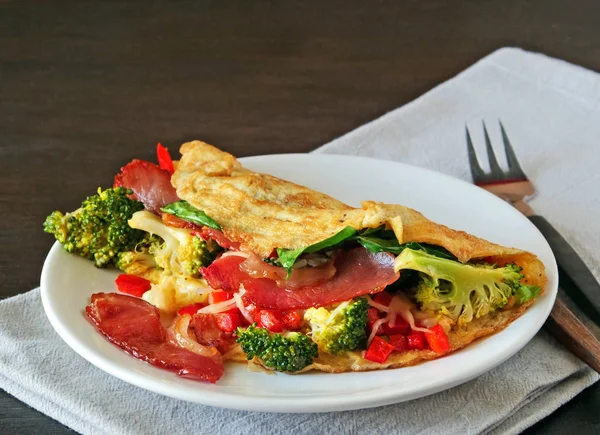Omelete saboroso com bacon, queijo, espinafre e brócolis na placa branca — Fotografia de Stock