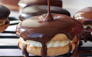 Çikolatalı ganache 'yi tel askıda sandviç kurabiyelerinin üzerine damlatıyor.