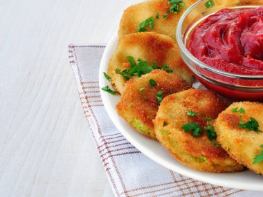 Beyaz ahşap masada bir kase ketçapla haşlanmış kabaklı cips.