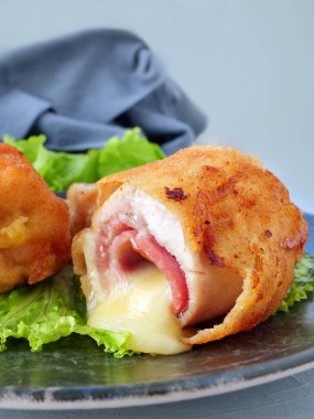 Tavuk cordon bleu şnitzel, jambon ve peynire sarılmış et, tabakta kızartılmış ve dikey.