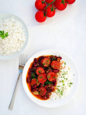 Beyaz masa üzerinde sosisli fasulye ve pirinç, dikey.