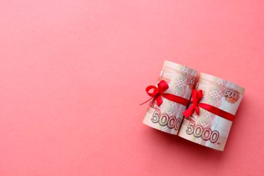 Rus para 5000 ruble bir tüp içine bükülmüş ve renkli bir arka plan üzerinde, bir kurdele ile bağlı