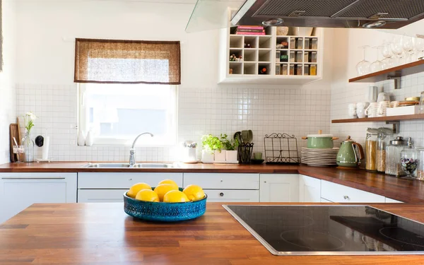 lemons in bowl on wooden counter top with kitchen on background