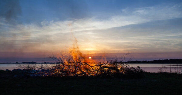 Silhouette of bonfire by the sea in the sunset