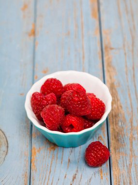 Kopya alanı ile mavi ahşap bir kase içinde Delicious Fresh ahududu