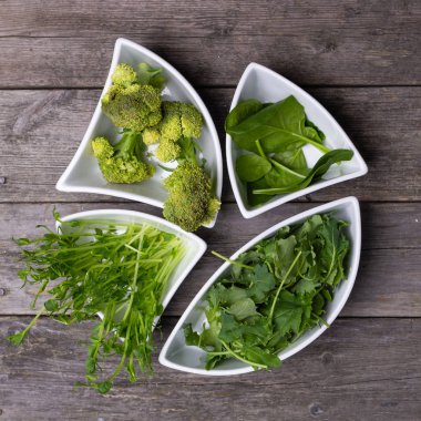 yukarıdan ahşap masada kase çiğ gıda yeşil salata