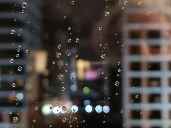 Image of water rain drops on the back of the building in the window.
