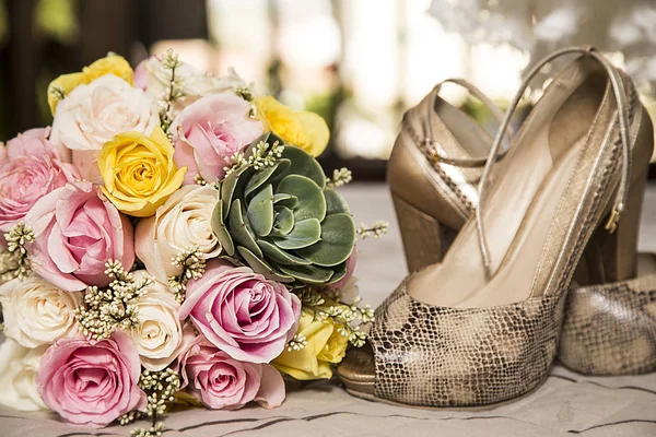 Wedding arrangement before the wedding. yoke with variety of roses and succulent. shoes and the bottom of the dress
