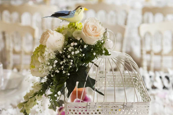 table with birds as decoration- Table of wedding decoration in elegant style. white tablecloth, glass plates and glasses. Pot with hydrangea and decoration with vintage birds